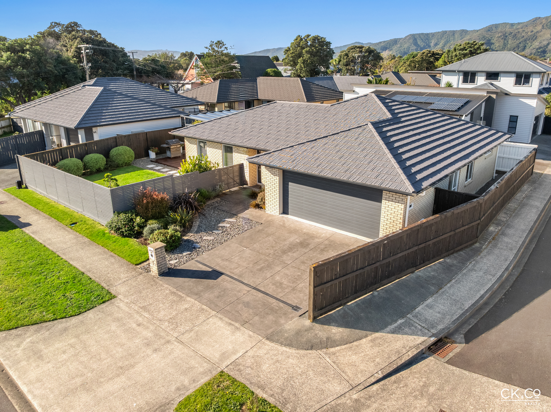 Aerial view of brick home with mountain backdrop, MacDiarmid Place